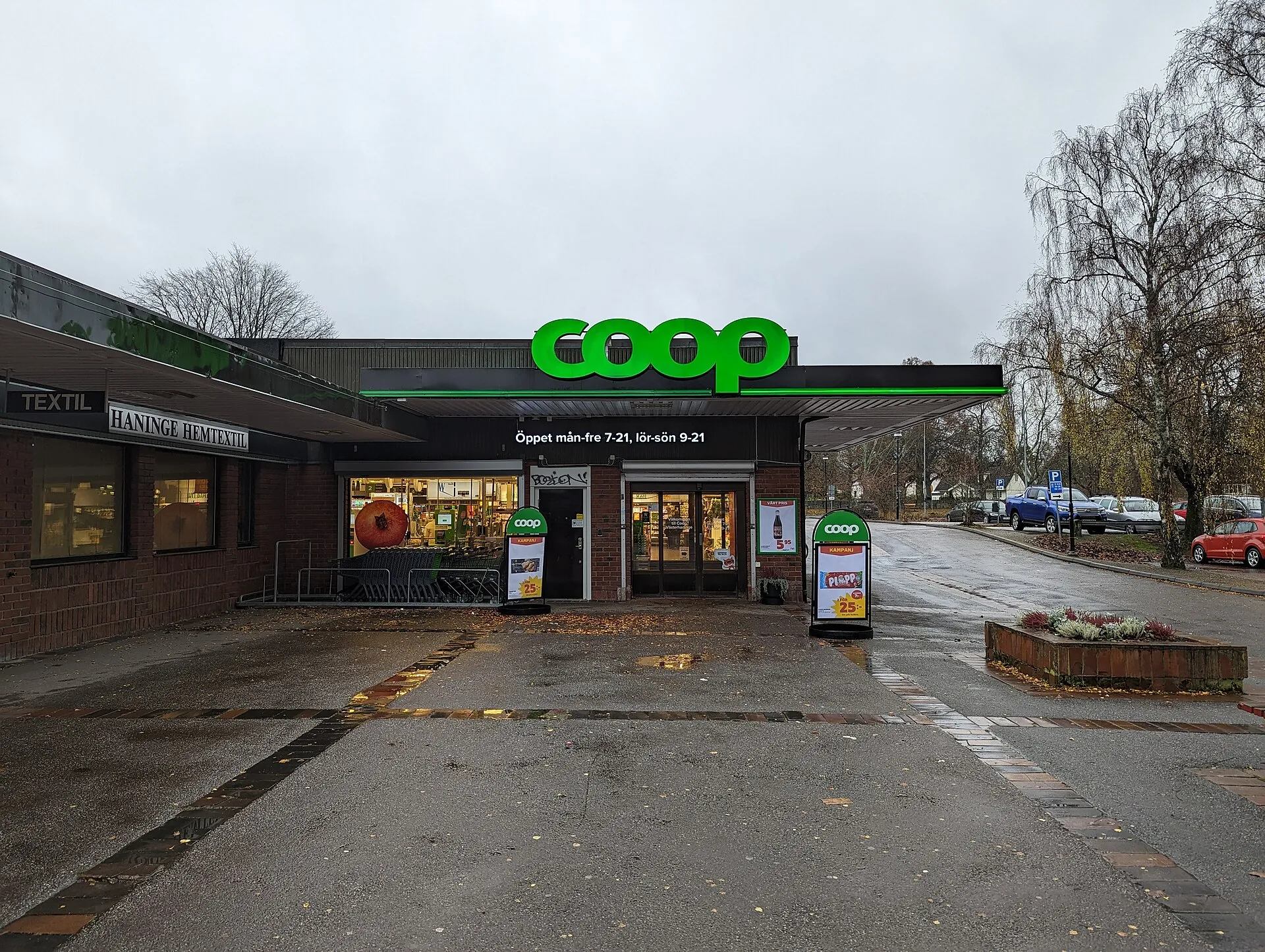 A Coop supermarket with its green sign on a wet autumn day