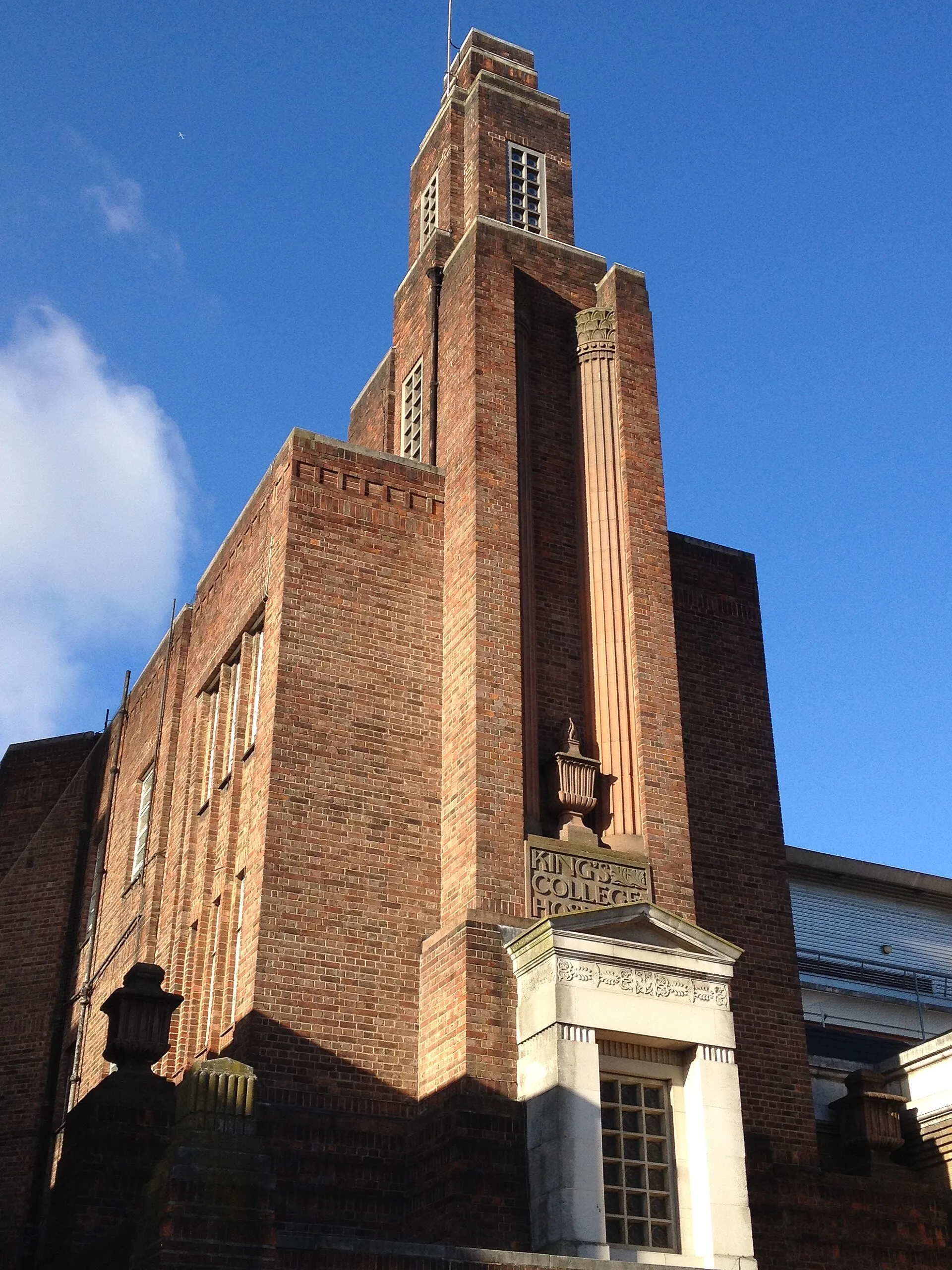The brick clock tower of King’s College Hospital against a blue sky