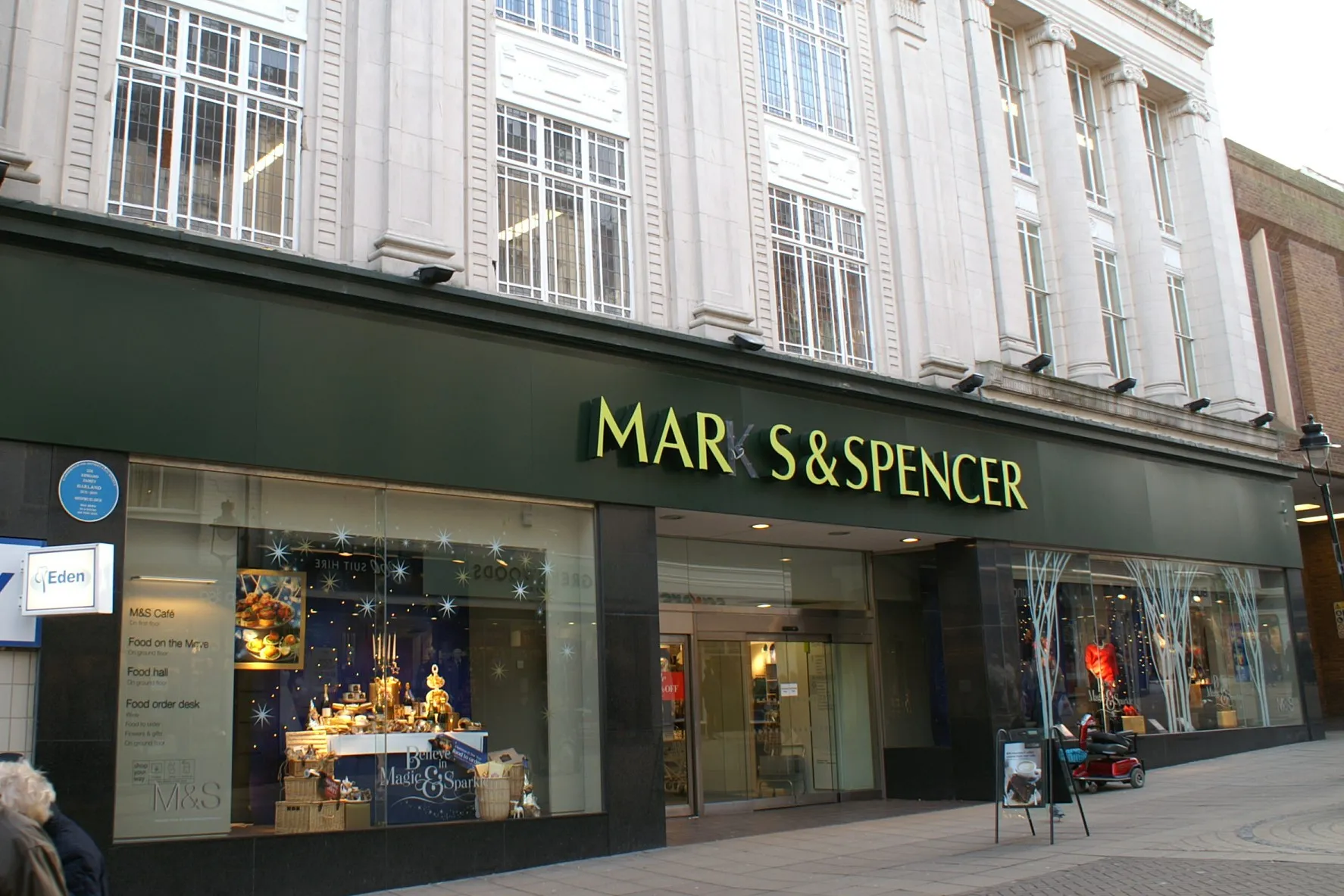 The front of a Marks & Spencer department store with lit shop windows